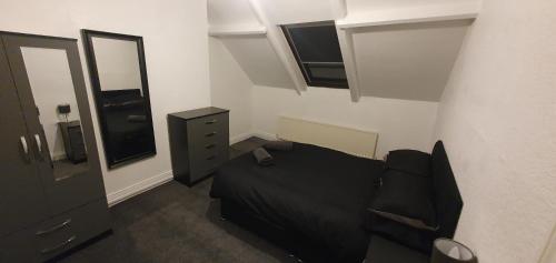 a small bedroom with a black bed and a dresser at Hustlers inn apartment in Newcastle upon Tyne
