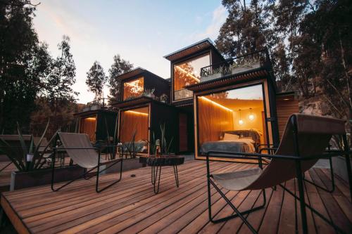 a house with a bed and chairs on a deck at Hawkay Glamping in San Miguel de Salcedo