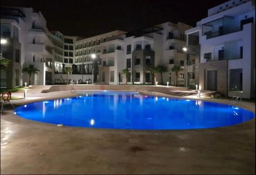 a large blue pool in front of some buildings at night at Luxury spacious 3 Bed apt with pool in Agadir