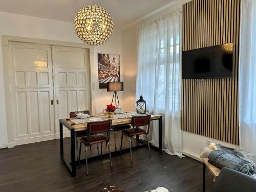 Zimmer mit einem Tisch mit Stühlen und einem Kronleuchter in der Unterkunft bee Design Apartment + Zentral + Küche + Parken in Wetzlar
