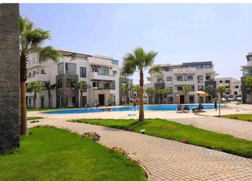 a resort with a pool and palm trees and buildings at Luxury spacious 3 Bed apt with pool in Agadir