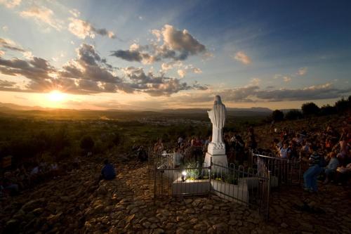 a crowd of people standing around a statue at sunset at Hotel Pax Cordis in Međugorje