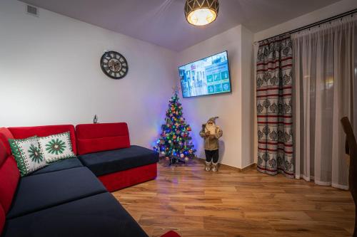 a christmas tree in a living room with a red couch at Domki Bukowianka in Murzasichle