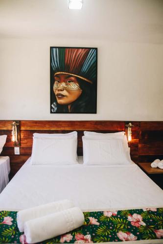 a bedroom with a bed with a painting on the wall at Pousada Reserva Tatuamunha in Pôrto de Pedras