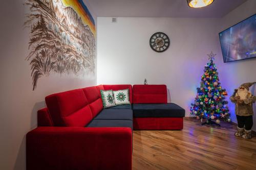 a living room with a red couch and a christmas tree at Domki Bukowianka in Murzasichle