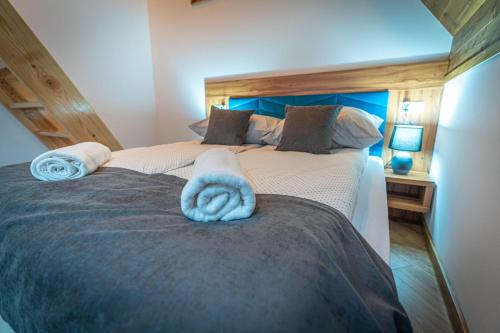 a bedroom with a large bed with a blue towel on it at Domki Bukowianka in Murzasichle