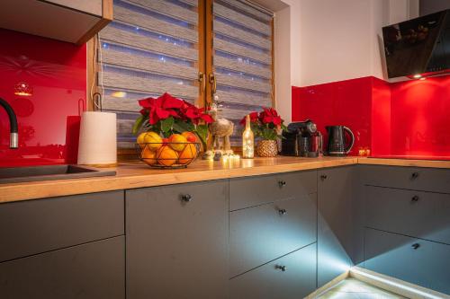 a kitchen with red walls and a counter with a bowl of fruit at Domki Bukowianka in Murzasichle
