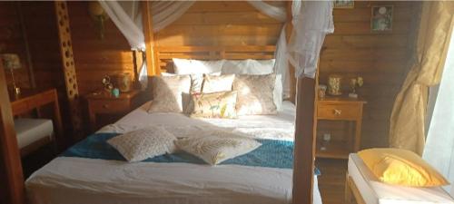 una camera da letto con letto, lenzuola e cuscini bianchi di Country Lodge La Pléiade a Sainte-Anne