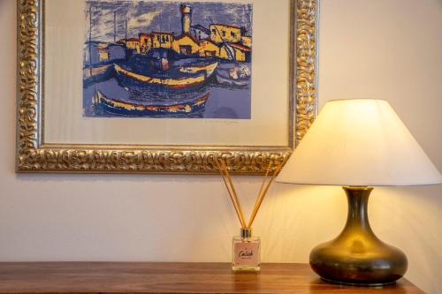 a lamp sitting on a table next to a painting at RelaisApartments PORTO in Alghero