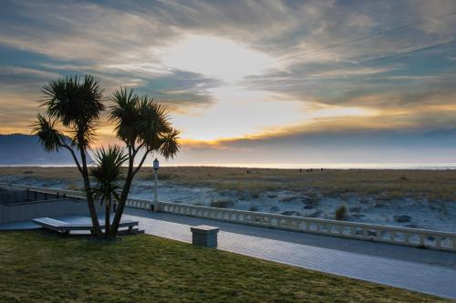 a palm tree and a bench next to a fence at Inn of the Four Winds Seaside Oceanfront in Seaside
