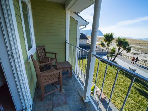 a porch with two chairs and a table and a view of the beach at Inn of the Four Winds Seaside Oceanfront in Seaside