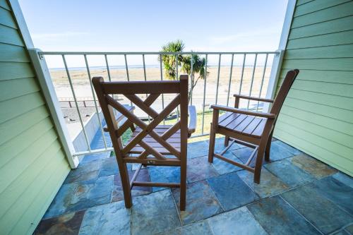 two chairs sitting on a balcony with the beach at Inn of the Four Winds Seaside Oceanfront in Seaside
