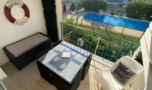- un balcon avec une table et une piscine dans l'établissement APPARTEMENT 4 PERSONNES PORT GRIMAUD - COTE D'AZUR, à Grimaud