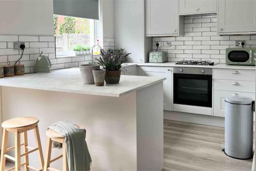 a kitchen with white cabinets and a counter with stools at The Cottage, a perfect getaway! in Southport