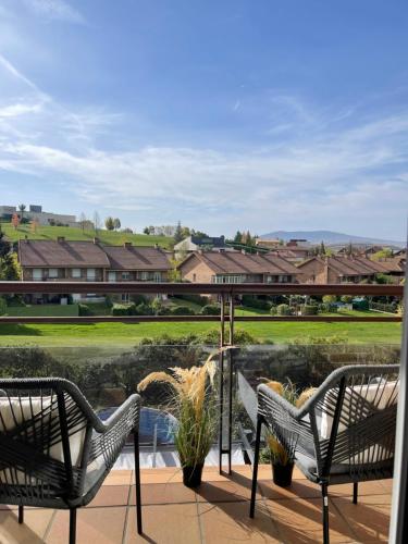2 sedie su un balcone con vista su un campo da golf di Estilosa casa golf suites a Gorraiz
