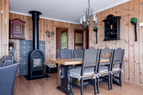 Sunne Stugcenter 12 في Gräsmark: غرفة طعام مع موقد خشبي وطاولة وكراسي