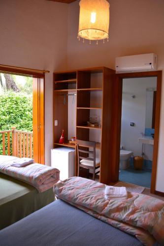 a bedroom with two beds and a desk and a kitchen at Pousada Asa do Vento in São Luiz do Paraitinga