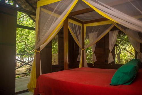 a bedroom with a canopy bed in front of a window at Ciamat Camp in Santo Amaro