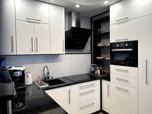 a kitchen with white cabinets and a black counter top at Apartament Tuwima 6 in Ełk