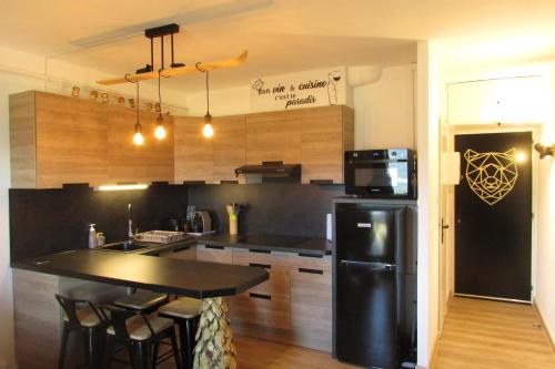 a kitchen with a black refrigerator and a table at Studio Cocooning tout confort Les Angles in Les Angles