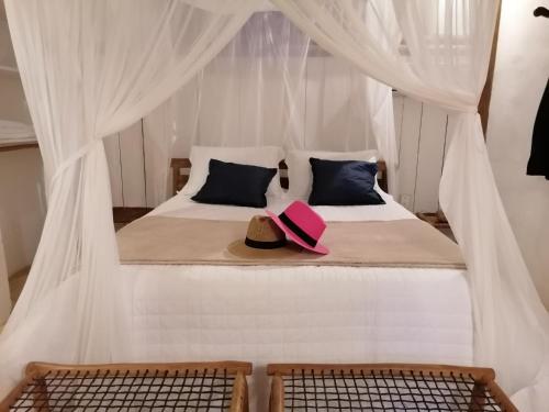 a bedroom with a bed with two hats on it at Trancoso Jungle Lodge in Trancoso