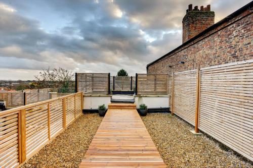 a balcony with a wooden walkway next to a brick building at The Penthouse - Allocated Parking with City Views in Ripon
