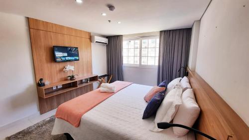 um quarto com uma cama e uma televisão na parede em Flat 217 Granja Brasil - Com Piscina Aquecida Em Itaipava em Itaipava