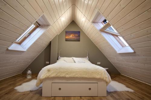 een slaapkamer met een bed op een zolder met dakramen bij Domek na Wichrowym Wzgórzu in Dursztyn