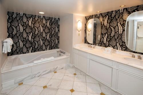 een badkamer met 2 wastafels, een bad en een tubermott bij Beau Rivage Resort & Casino in Biloxi