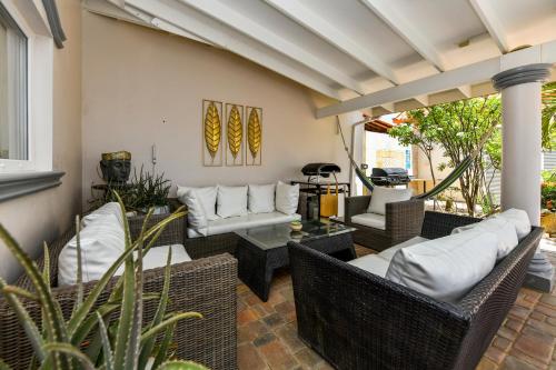 a patio with wicker chairs and a table at Villa Swiss Paradise with private pool in Palm-Eagle Beach