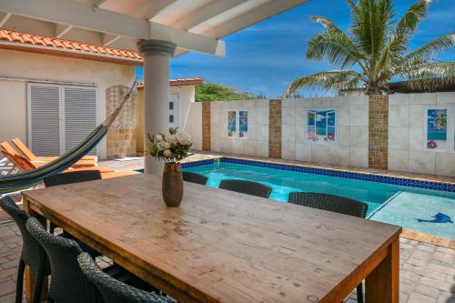 a table with chairs next to a swimming pool at Villa Swiss Paradise with private pool in Palm-Eagle Beach