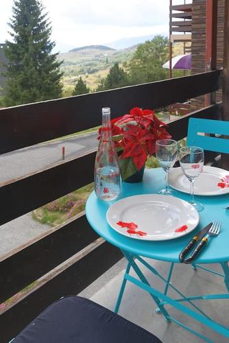 une table avec deux assiettes, une bouteille et des verres dans l'établissement Le balcon cerdan, à Font-Romeu-Odeillo-Via