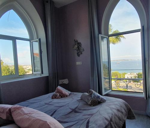 a bedroom with two large windows and a bed at Best seaview Penthouse+77m2 privat roof terrace near beach and Cannes in Vallauris