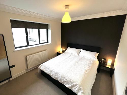 a bedroom with a white bed and a window at Modern and cozy 2-guest flat with gated parking in Kingston upon Thames