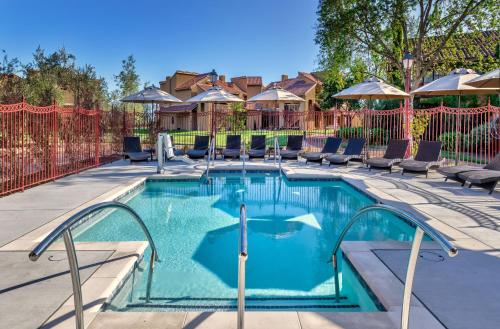a swimming pool with chairs and a fence at Vintners Resort in Santa Rosa