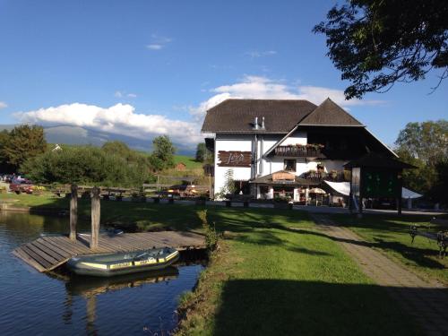 a building with a boat on the water in front of it at Jerà am Furtnerteich Hotel-Ristorante&Relax in Mariahof