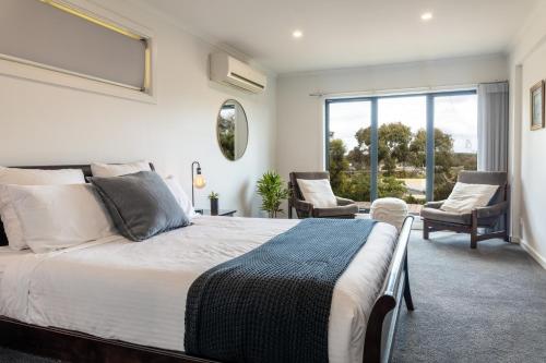 a bedroom with a large bed and two chairs at OASIS ON SUNSET - tranquility close to the ocean in Ocean Grove
