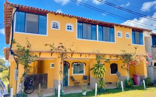 uma casa amarela com um telhado vermelho em Guest House Renascer K&W em Cabo Frio