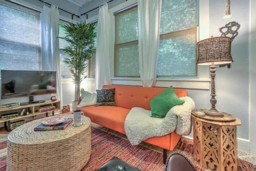 a living room with an orange couch with green pillows at Urban Zen Great Location in Memphis