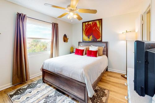 a bedroom with a bed with red pillows and a ceiling fan at Villas on the Gulf H10 in Pensacola Beach