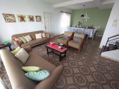 a living room with a couch and chairs and a table at Férias e alegrias em casa pé na areia! in Penha