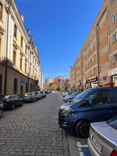 una calle adoquinada con coches aparcados en una ciudad en Apartament Akademia, en Legnica