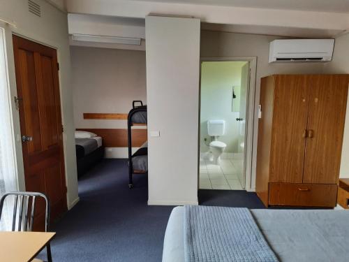 a hotel room with a bed and a bathroom at Abbotswood Motor Inn in Geelong