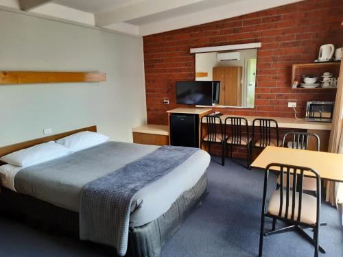 a hotel room with a bed and a table and chairs at Abbotswood Motor Inn in Geelong