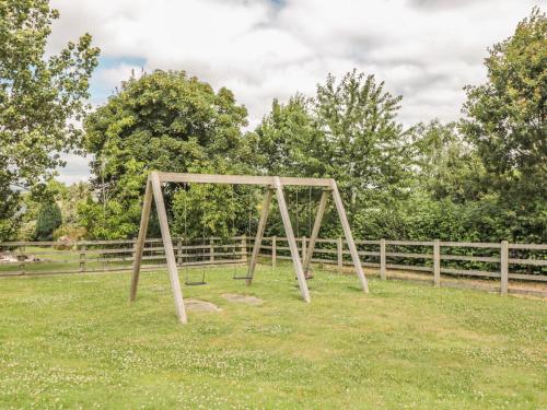 a wooden frame in the grass in front of a fence at Oak Apple in Newton Abbot