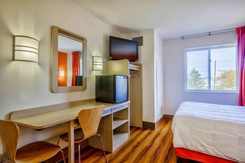 una camera d'albergo con scrivania, letto e specchio di Motel 6-Burlington, ON - Toronto West - Oakville a Burlington