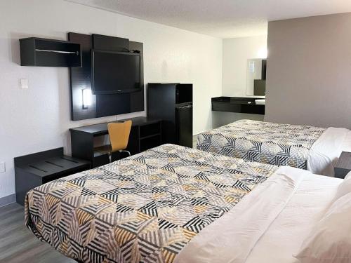 a hotel room with two beds and a flat screen tv at Motel 6 Baton Rouge Southeast in Baton Rouge