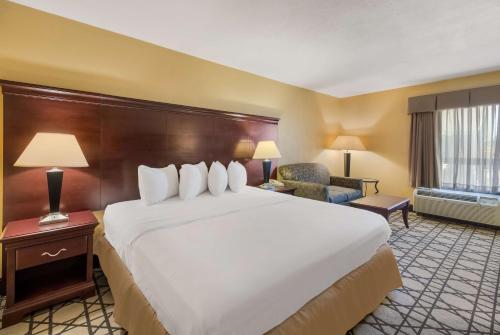 um quarto de hotel com uma cama grande e uma cadeira em Best Western University Inn em Murray