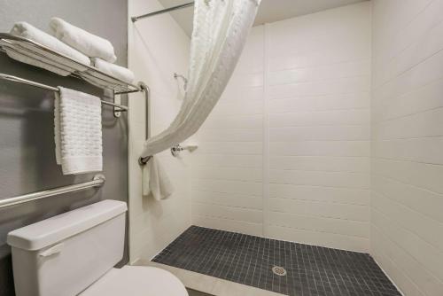 a bathroom with a toilet and a shower with towels at SureStay Hotel by Best Western Deer Park in Deer Park