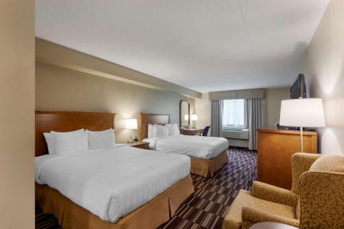 una habitación de hotel con 2 camas y una silla en Best Western Plus Orillia Hotel, en Orillia